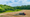 A tractor is spraying finally ground rock on a field.